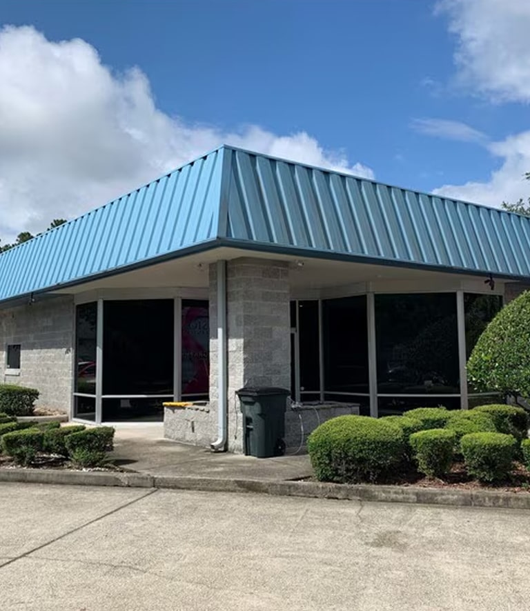 A commercial building with a blue roof and gray brick walls.
